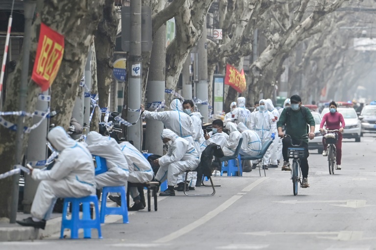 Workers in protective clothing sit near a locked-down area after the detection of new cases of Covid-19 in Shanghai on March 14. Workers in protective clothing sit near a locked-down area after the detection of new cases of Covid-19 in Shanghai on March 14.