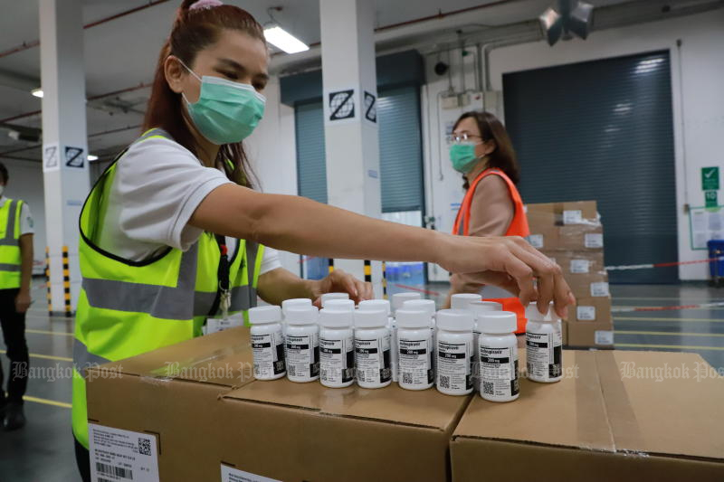 Public Health Ministry staff check bottles of the antiviral drug molnupiravir at a Zuellig Pharma warehouse in Samut Prakan’s Bang Sao Thong district, before distributing the medication to groups of high-risk Covid-19 patients. (Photo: Somchai Poomlard)