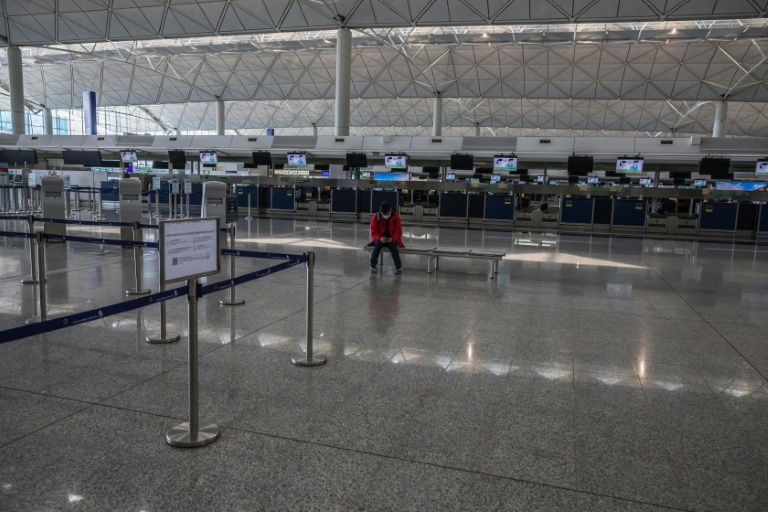 A man sits in front of check-in counters at Hong Kong International Airport. A man sits in front of check-in counters at Hong Kong International Airport.