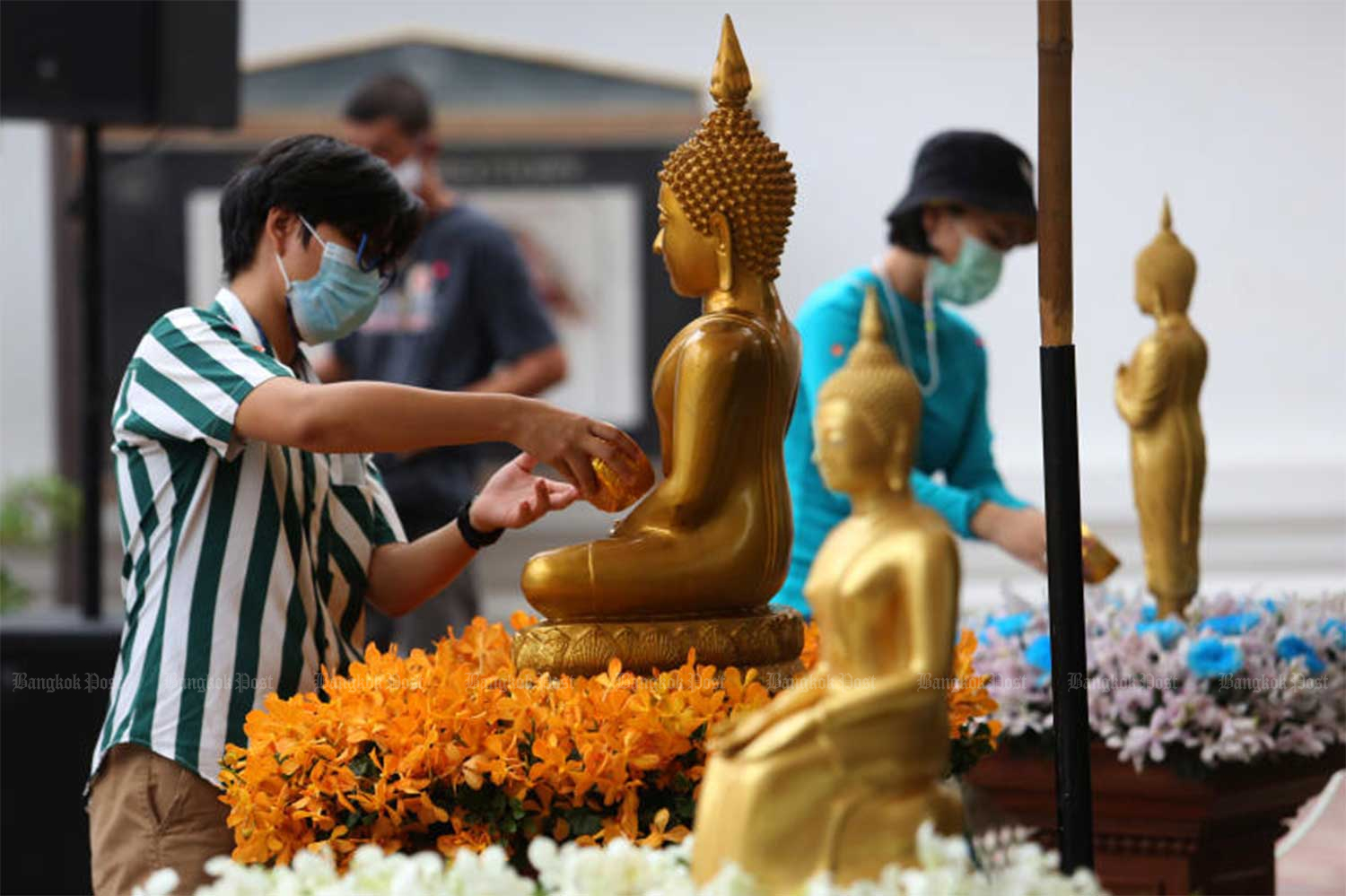 People pour scented water on Buddha statues at Wat Pho in Bangkok during the splashing-free Songkran festival last year. (File photo)