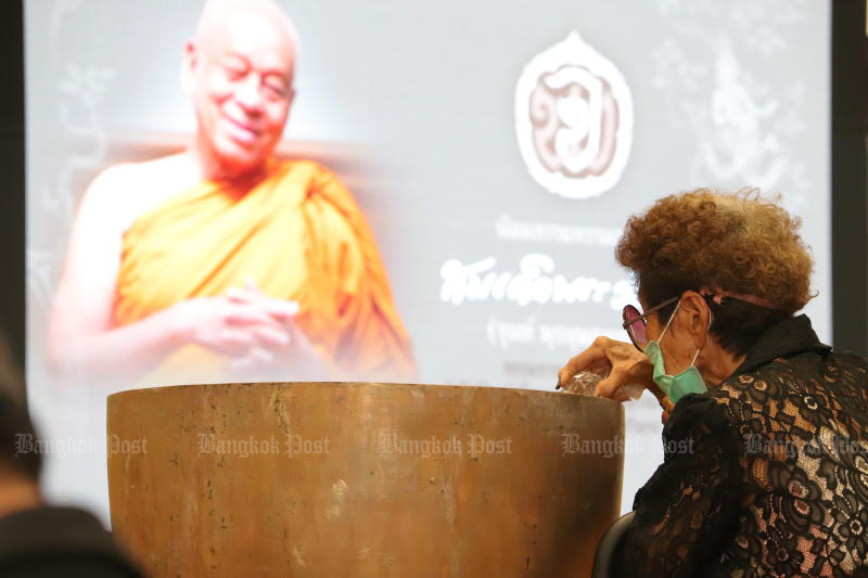 A worshipper attends a royally-sponsored bathing rite in front of a picture of the late Somdet Phra Wannarat, on March 17, 2022 at Wat Bowonniwet Vihara. The revered monk died of gall bladder cancer on March 15. (Photo: Pornprom Satrabhaya)