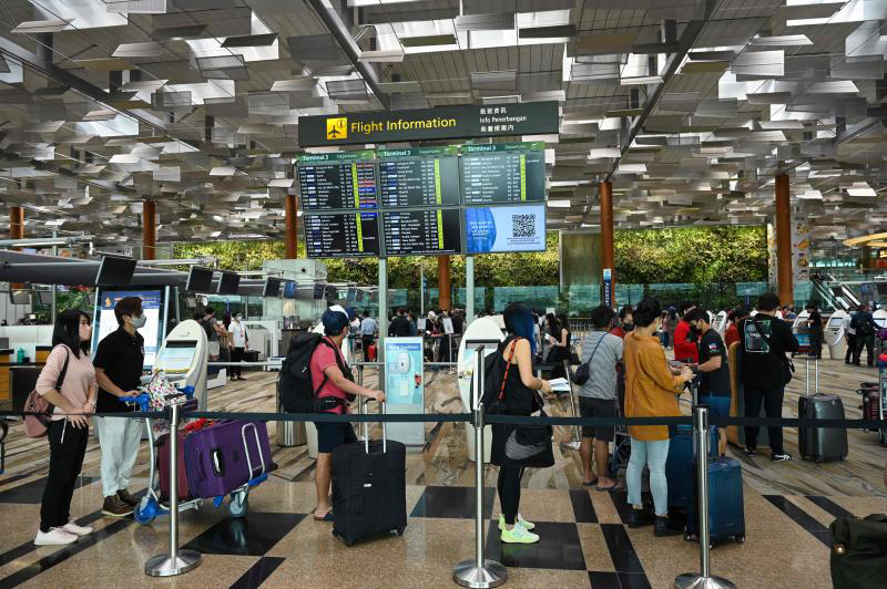 Travellers queue for self check-in before departure at Changi International Airport on Friday, as Singapore reopened its land and air borders to travellers fully vaccinated against the Covid-19 coronavirus. (AFP photo)