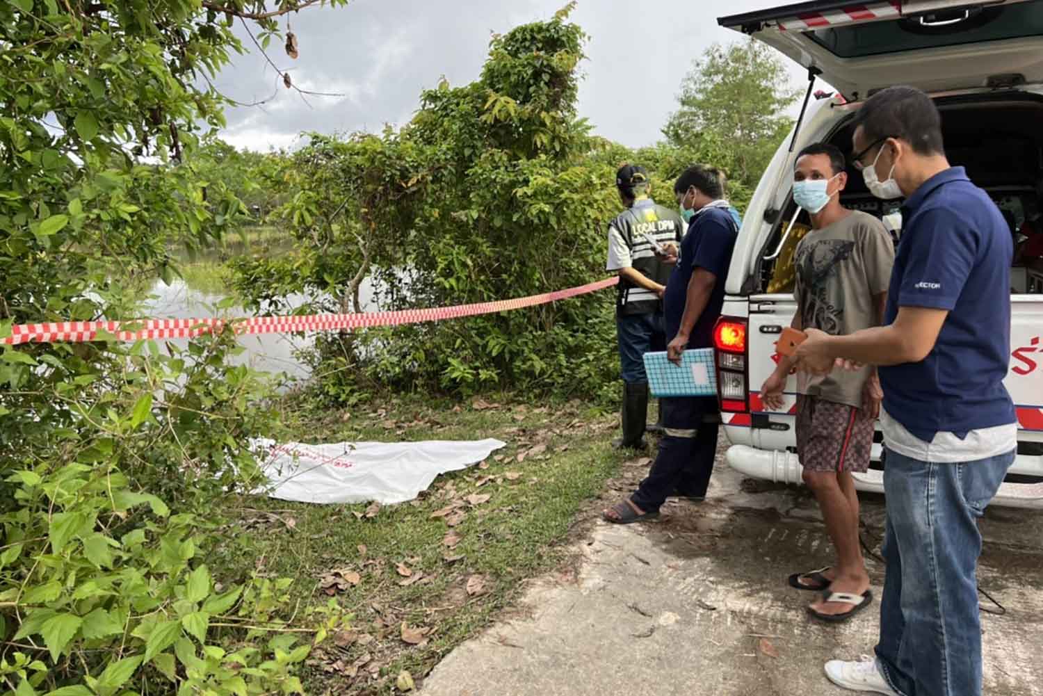 Police and rescuers beside the flooded rice field where a man drowned while fishing in Phra Phrom district, Nakhon Si Thammarat, on Wednesday afternoon. (Photo: Nujaree Rakrun)