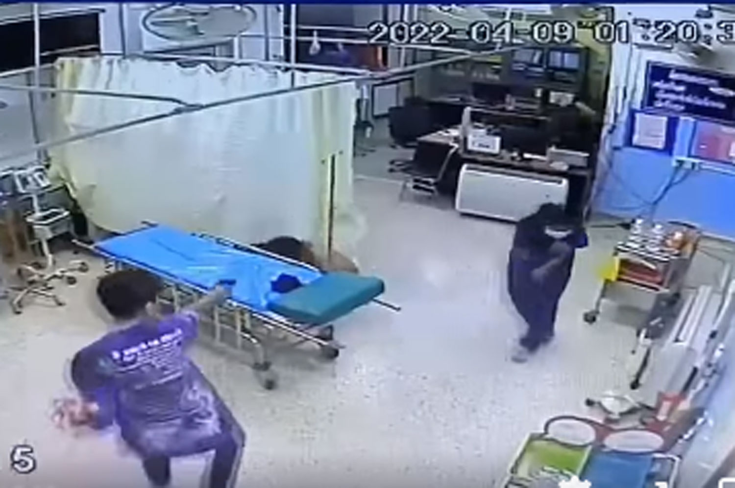 Security video shows a man firing shots at a rival who has fallen off a gurney in the emergency room at Pak Khat Hospital early Saturday. (Image from a video posted by Bueng Kan news Facebook page)