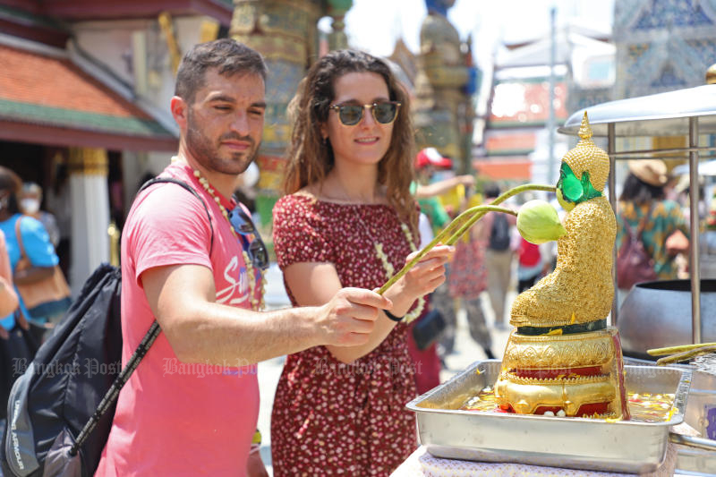 A visitor pours water on Buddha images to usher in the Thai new year marked by the three-day Songkran festival at the Temple of the Emerald Buddha on April 13, 2022. (Photo: Varuth Hirunyatheb)