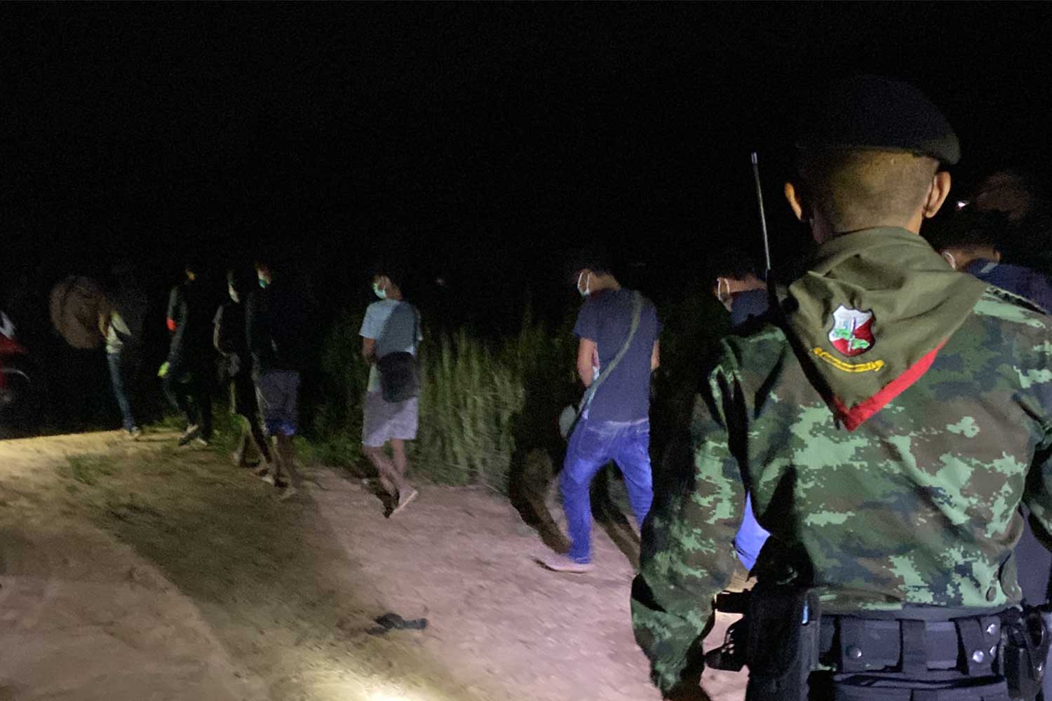 The 20 Myanmar nationals are led away from the dirt track where they were arrested, near the Malaysian border in Sadao district, Songkhla province, early Friday morning. (Photo: Assawin Pakkawan)