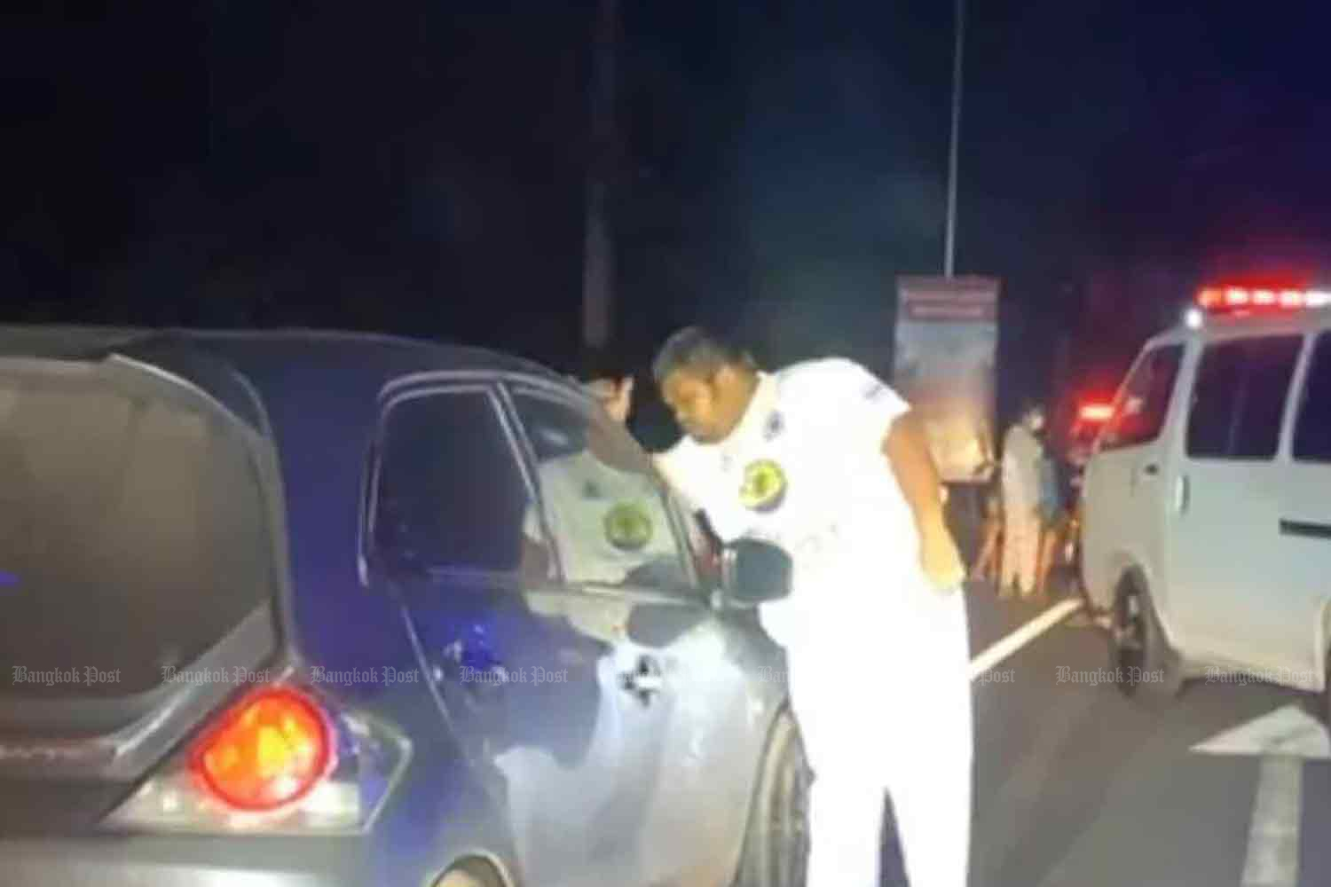 A rescuer peers into the car in which an estranged couple were found dead on a roadside in tambon Khok Kruat of Muang district, Nakhon Ratchasima, early on Tuesday morning. (Photo: Prasit Tangprasert)