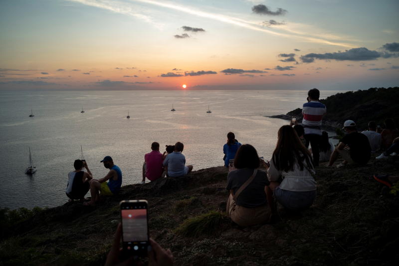 Locals and tourists watch a sunset from Phuket's Phromthep Cape on April 9, 2022. (Reuters photo)