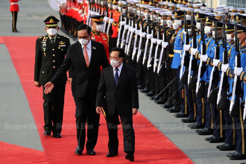 Prime Minister Prayut Chan-o-cha gestures as he and Lao Prime Minister Phankham Viphavanh review a guard of honour at Government House on Wednesday. (Photo: Wichan Charoenkiatpakul)