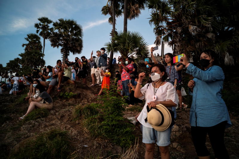 Locals and tourists wearing protective masks watch a sunset from Phuket's Phromthep Cape on April 9, 2022. (Reuters photo)