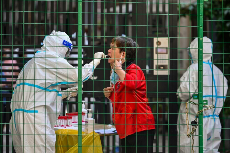 A Health worker takes a swab sample from a woman at the entrance of a residential area under Covid-19 lockdown in the Xuhui district of Shanghai. A Health worker takes a swab sample from a woman at the entrance of a residential area under Covid-19 lockdown in the Xuhui district of Shanghai.
