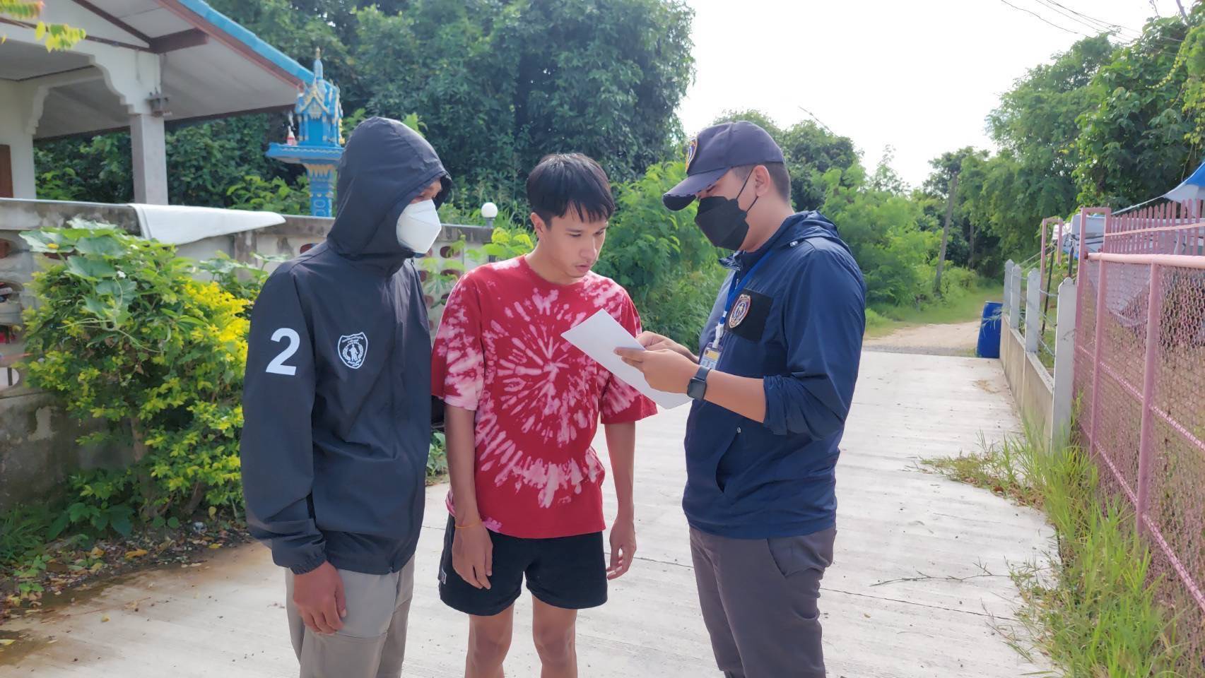 Police officers question Nitikorn Manop, centre, at a house in Cha-am district, Phetchaburi province. (Photo supplied)