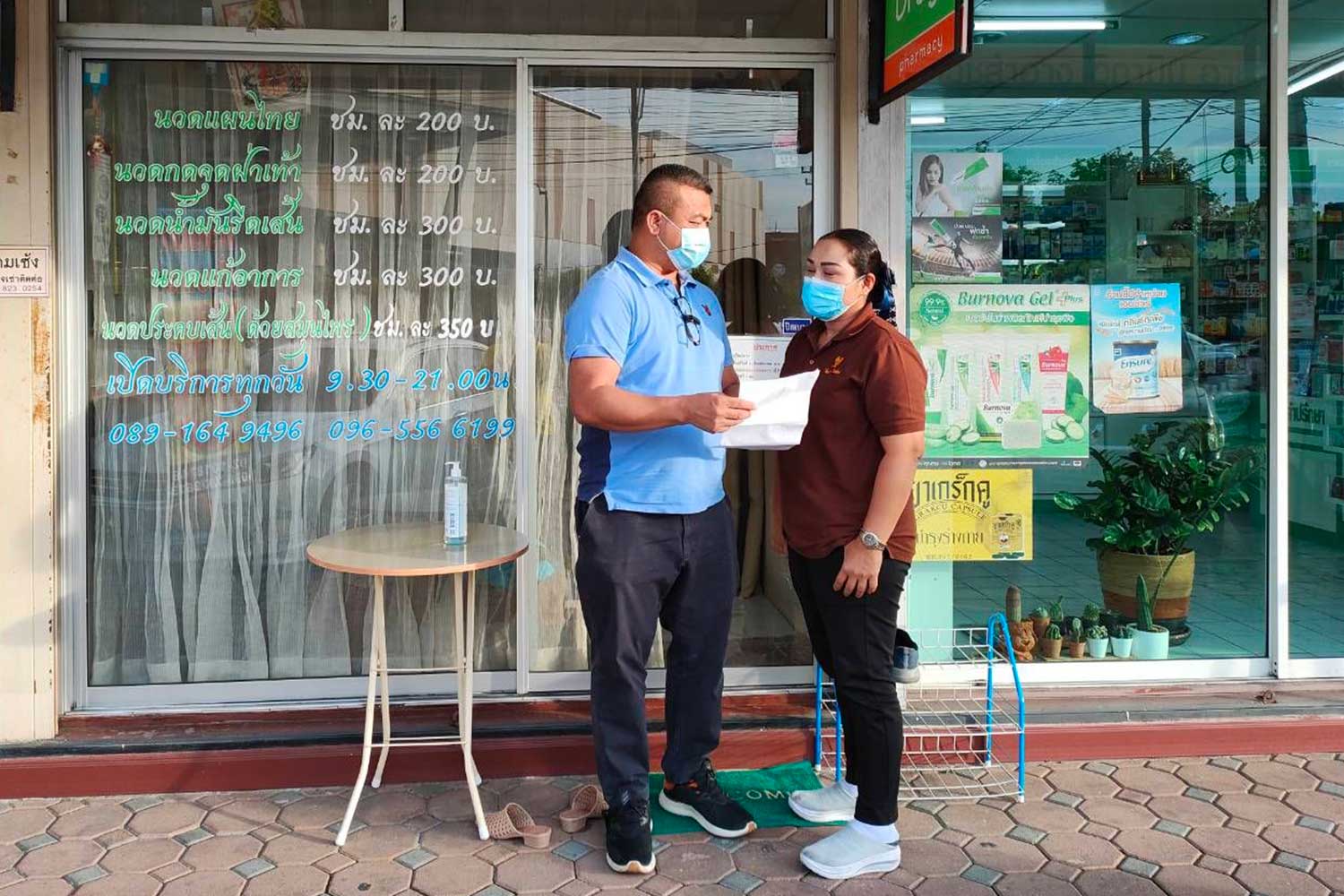 A police officer serves an arrest warrant on Charoensri Thongkham, 41, in front of the Na Sabai Thai traditional massage shop in Bangkok’s Bang Khen district, on Tuesday. (Photo supplied)