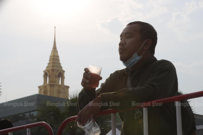 A man has a drink outside parliament in Bangkok on Feb 9 during a rally held to demand legal amendments to make it easier for small-scale distillers and brewers to operate. A bill to that effect passed first reading in the House on June 8. (Photo: Pornprom Satrabhaya)