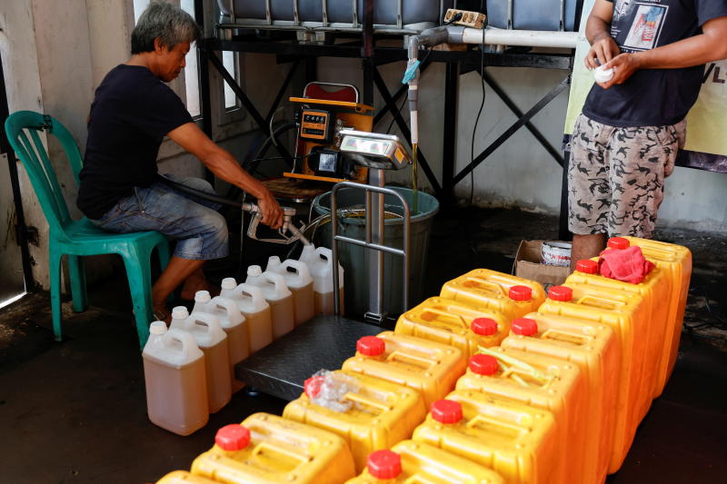 A worker fills jerrycans with cooking oil at a distribution station in Jakarta, Indonesia, May 20, 2022. (Reuters)