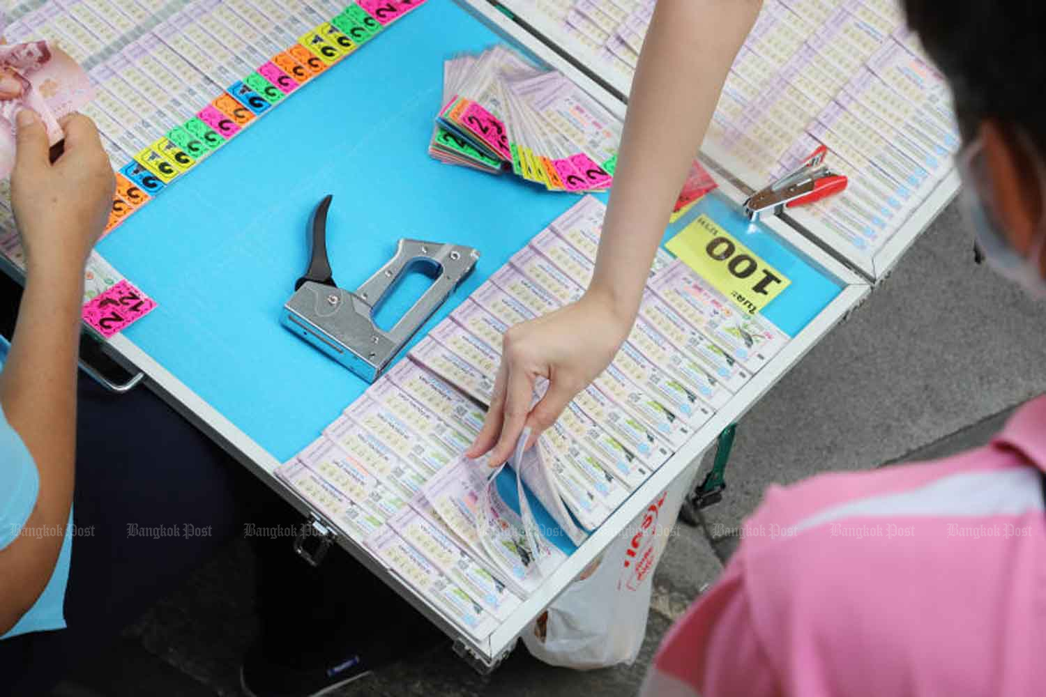 People pin their luck on lottery tickets sold by a street vendor in Pathumwan district, Bangkok. The price is 100 baht per ticket, which is 20 baht higher than the regulated price of 80 baht. (Photo: Apichit Jinakul)