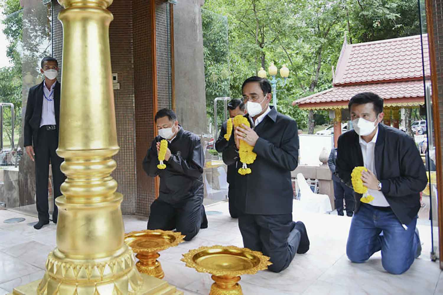 Prime Minister Prayut Chan-o-cha, flanked by Digital Economy and Society Minister Chaiwut Thanakamanusorn, right, and Labour Minister Suchart Chomklin, pays his respect to the city pillar in Muang district of Kamphaeng Phet where he inspected water management projects on Thursday. (Government House photo)