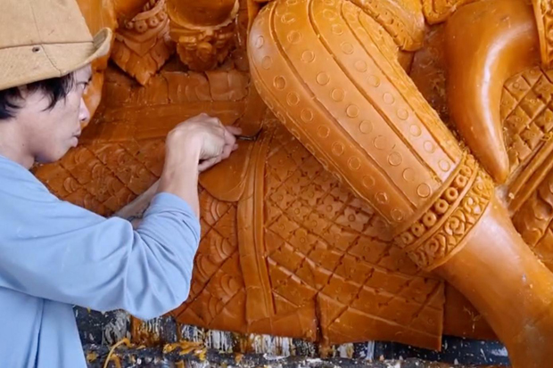 An artisan works wax candles into various shapes depicting episodes from the life of Lord Buddha.