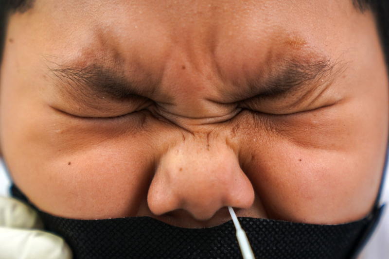 A health worker from Zendai organisation in personal protective equipment takes a swab sample from a boy for a rapid antigen test in Bangkok on Jan 5, 2022. (Reuters photo)