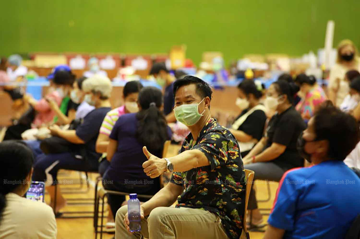 A man poses for a picture while being among people receiving Covid-19 vaccination at the Bangkok Youth Centre in Din Daeng district on July 21. (Photo: Apichart Jinakul).