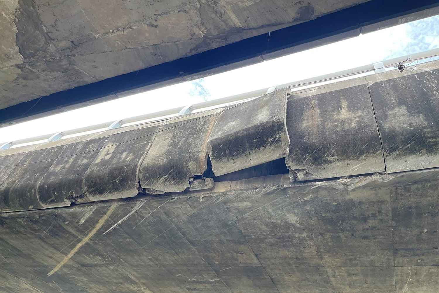 Concrete slabs hang loosely from the parapet of a flyover above Rama II Road in Muang district of Samut Sakhon on Wednesday morning. Motorists reported it to highway police, who promptly closed the traffic lanes beneath. (Photo: Highway police)