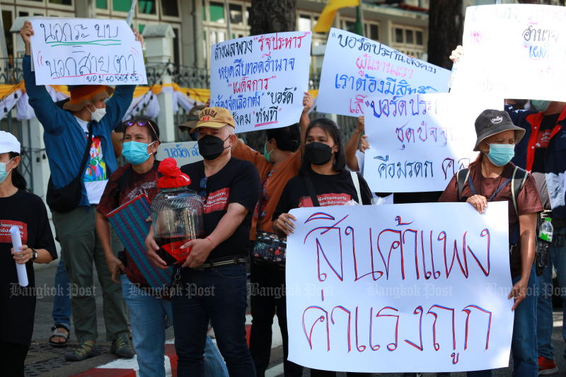 Protesters hold a sign saying ‘Prices of Goods Go Up, Wages Down’ as they demand a hike in the daily minimum wage for workers outside Government House on July 18, 2022. (Photo: Apichart Jinakul)