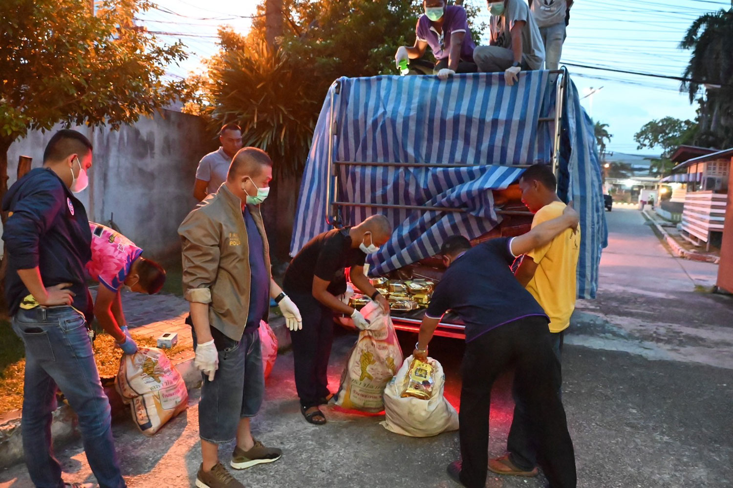 Narcotics suppression police officers remove fertiliser sacks filled with packs of crystal methamphetamine from a pickup truck as the driver (yellow shirt) looks on at a security checkpoint in Pattani on Friday. (NSB photo)