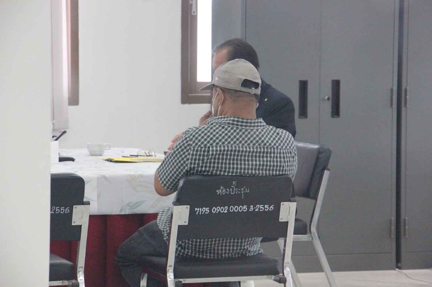 Somyos Panprasong, wearing a white cap, at Phlu Ta Luang police station where he surrendered on Tuesday morning to hear charges in connection with the Mountain B pub fire. (Photo: Chaiyot Pupattanapong)