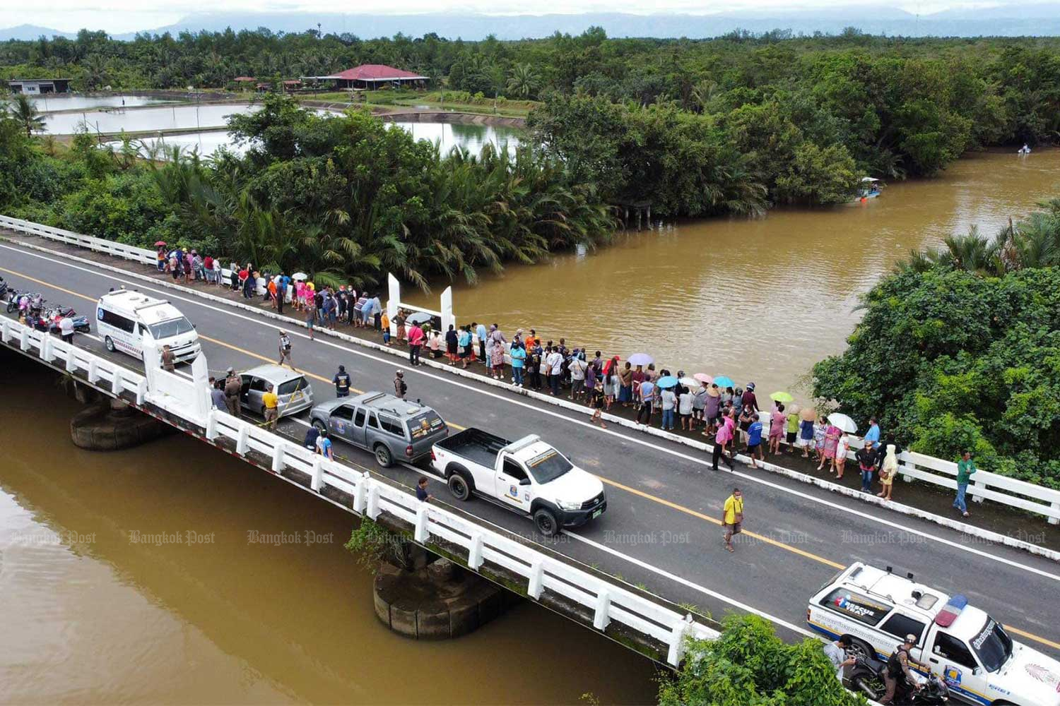 People gather on the bridge across Bang Phra canal in Muang district of Trat as rescue workers search for the two women teachers who jumped from there into the canal on Tuesday. (Photo:@sawangboontrat rescue Facebook page)