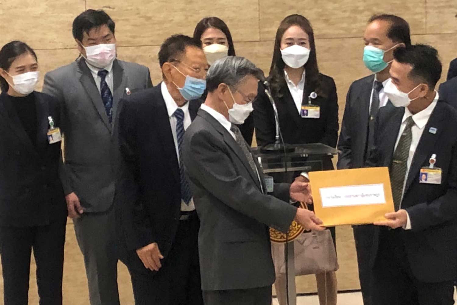 Pheu Thai leader Cholnan Srikaew, right, on Wednesday submits a petition seeking a Constitutional Court ruling on Prime Minister Prayut Chan-o-cha's eight-year limit to Parliament President Chuan Leekpai, left, for forwarding to the court. (Photo supplied)