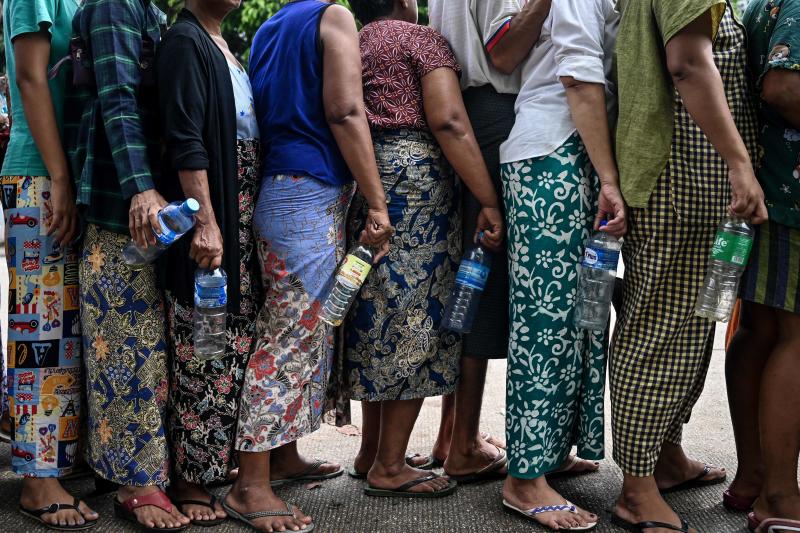 People queue with empty plastic bottles to buy cheap vegetable oil in Yangon on Thursday. (Photo: AFP)