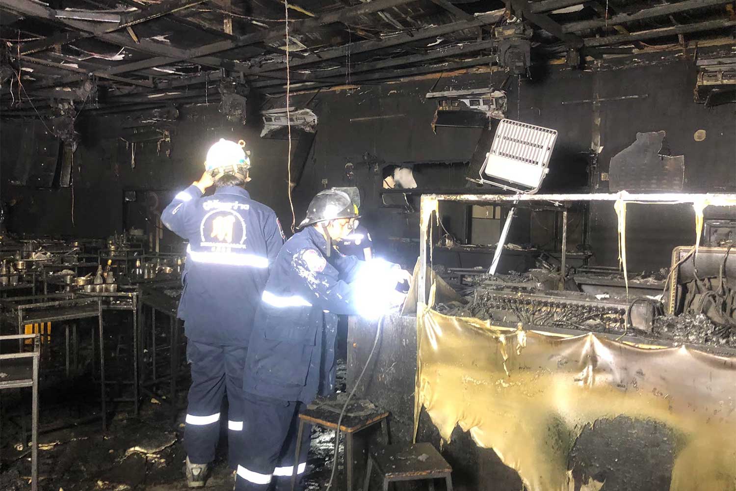 Rescue workers check the fire-gutted interior of the Mountain B pub in Sattahip on Aug 5. (Photo: Sawang Boriboon Rescue Foundation)