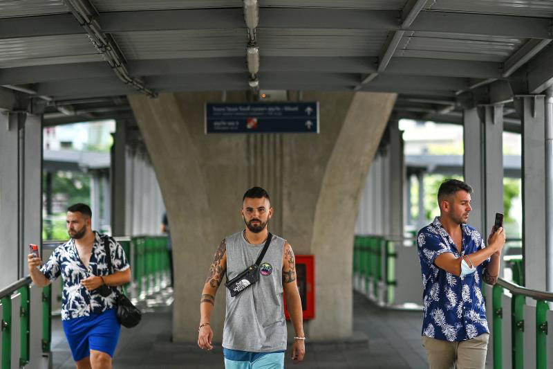 Tourists take photographs on an overhead bridge to a BTS Skytrain station in Bangkok on June 24, 2022. Thailand will introduce a new visa programme to allow more foreign professionals to work from the kingdom. (AFP photo)