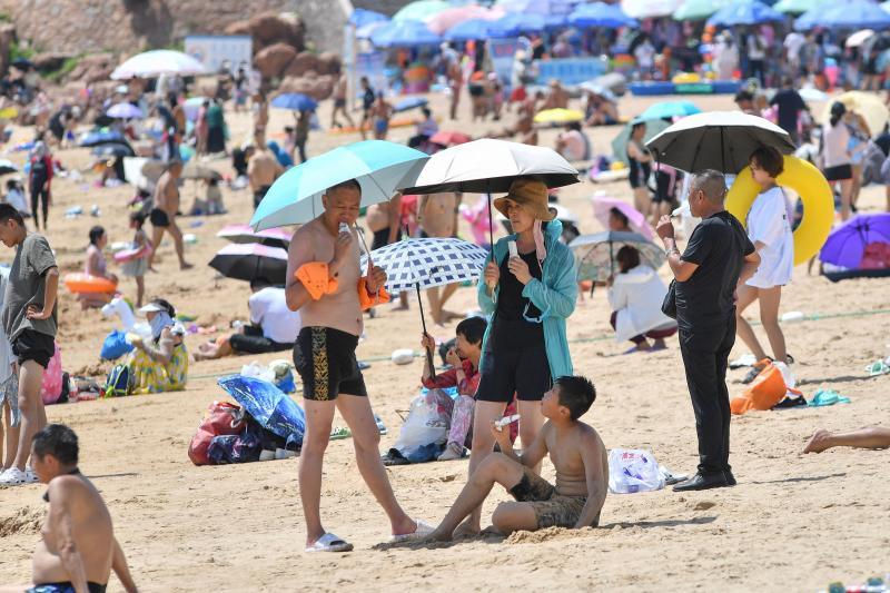 This photo taken on Aug 1, 2022, shows people using umbrellas as sunshade on a beach amid hot weather in Qingdao, in China's eastern Shandong province. (Photo: AFP)