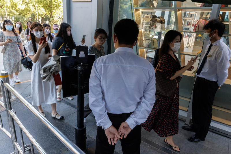 Security guards check the health code app of people entering a business area before office hours in Beijing on July 14, 2022. (Reuters photo)