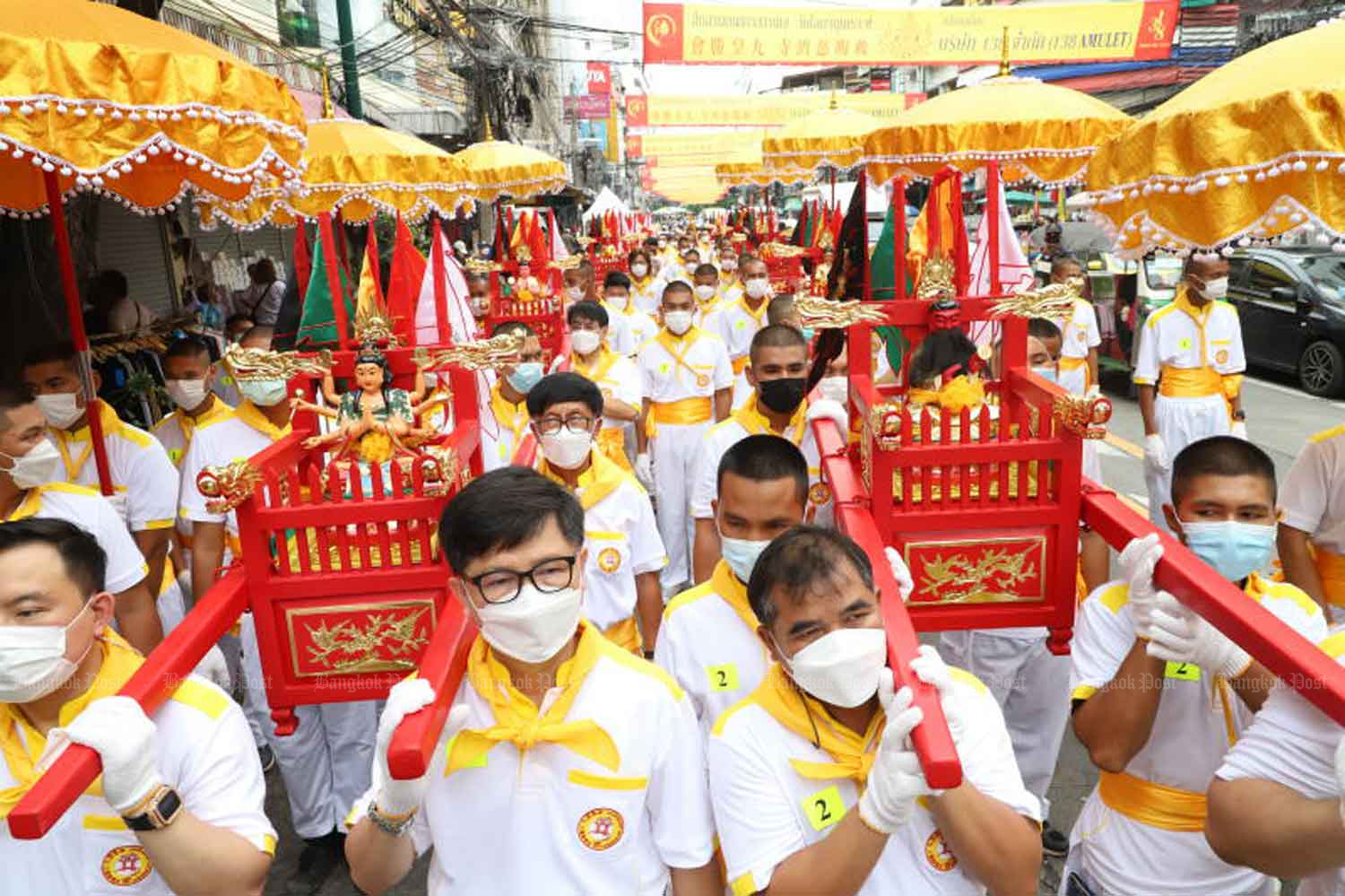 Devotees carry sedan chairs parading deities to the Odeon roundabout in the Yaowarat area of Bangkok on Sunday when the country logged 319 new Covid-19 inpatients and eight more fatalities related to the disease. (Photo: Wichan Charoenkiatpakul)