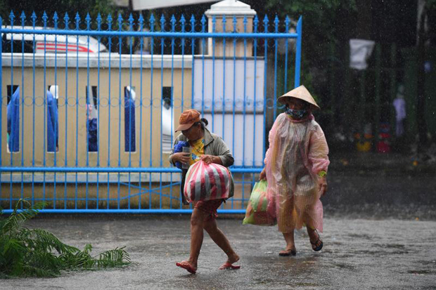 Two residents carrying supplies walk in the rain outside a primary school being used as a shelter during Typhoon Noru in Hoi An in Vietnam's Quang Nam province on Tuesday. (Photo: Reuters)