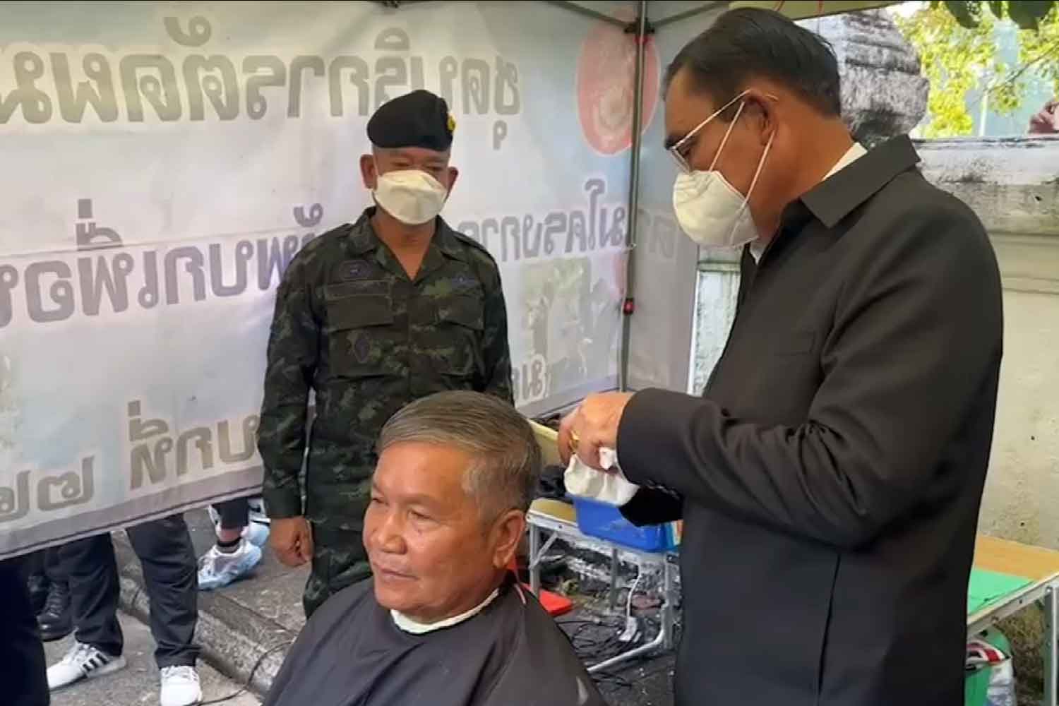 Prime Minister Prayut Chan-o-cha trims the hair of a veteran in Warin Chamrap district, Ubon Ratchathani province, on Tuesday. (Photo and video supplied)