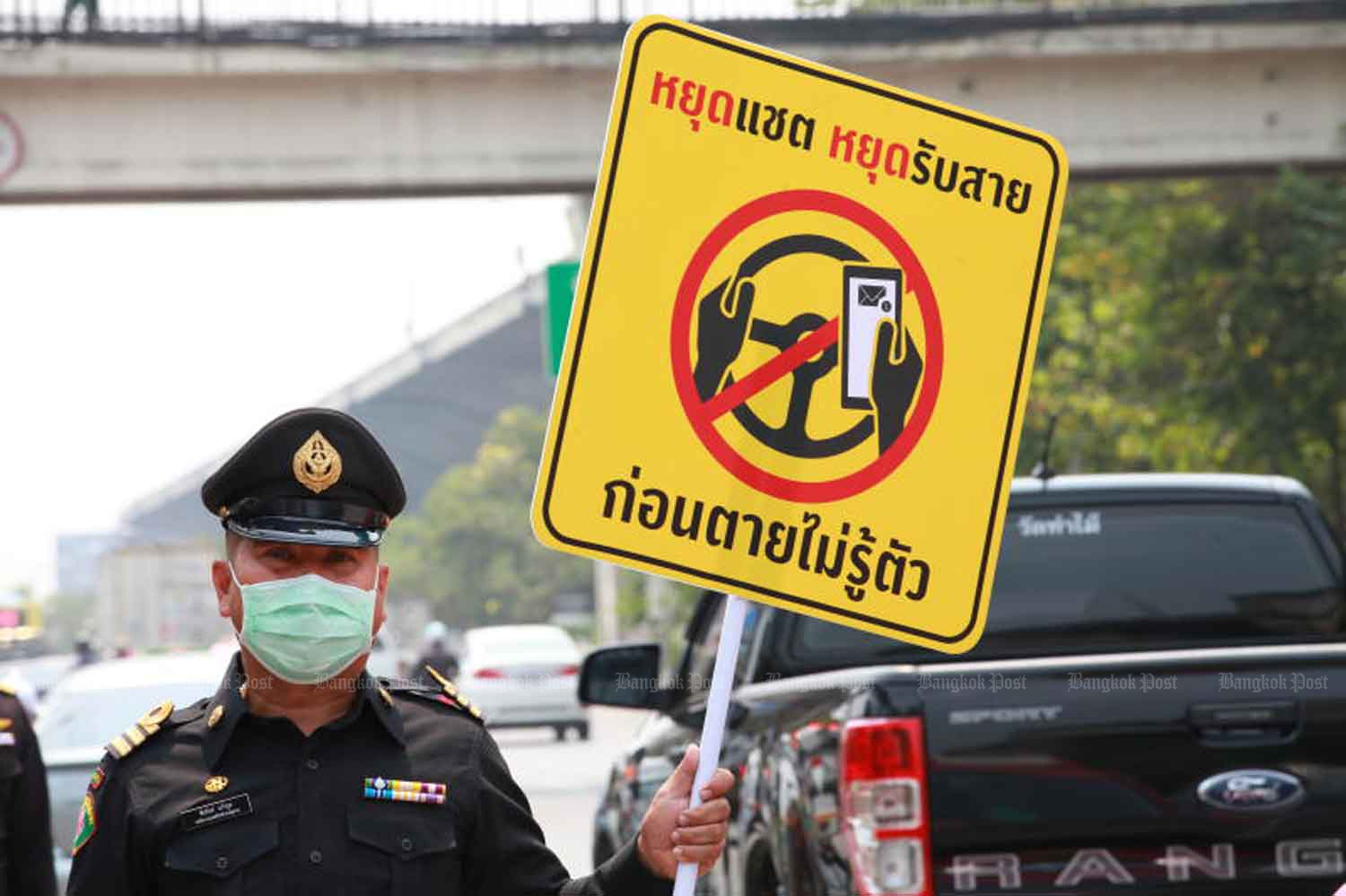 Chatree Watanakechorn, Bangkok deputy city clerk, raises a sign warning drivers not to use mobile phones while at the wheel, during the Songkran festival in April this year. (Photo: Apichart Jinakul)