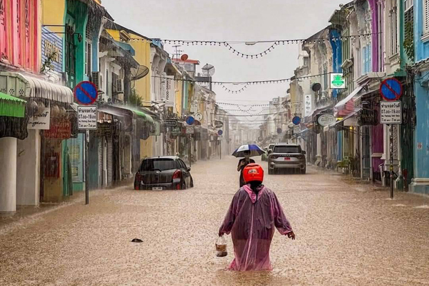 A woman wades along a flooded road in downtown Phuket on Sunday. (Photo: Achadtaya Chuenniran)