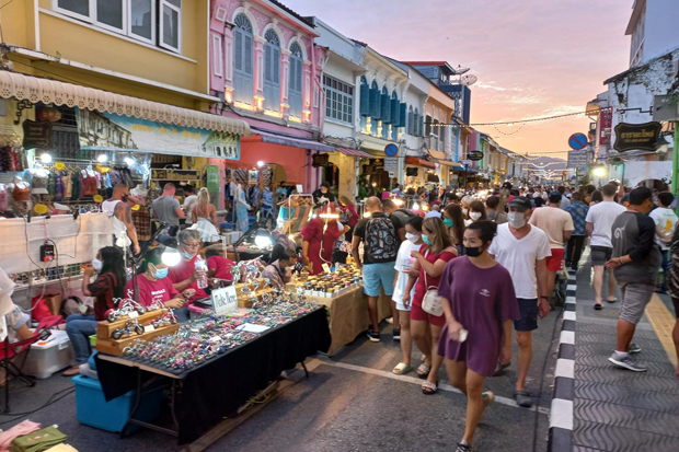 Tourists examine items on sale as they stroll along Phuket's walking street. (Photo: Achadthaya Chuenniran)