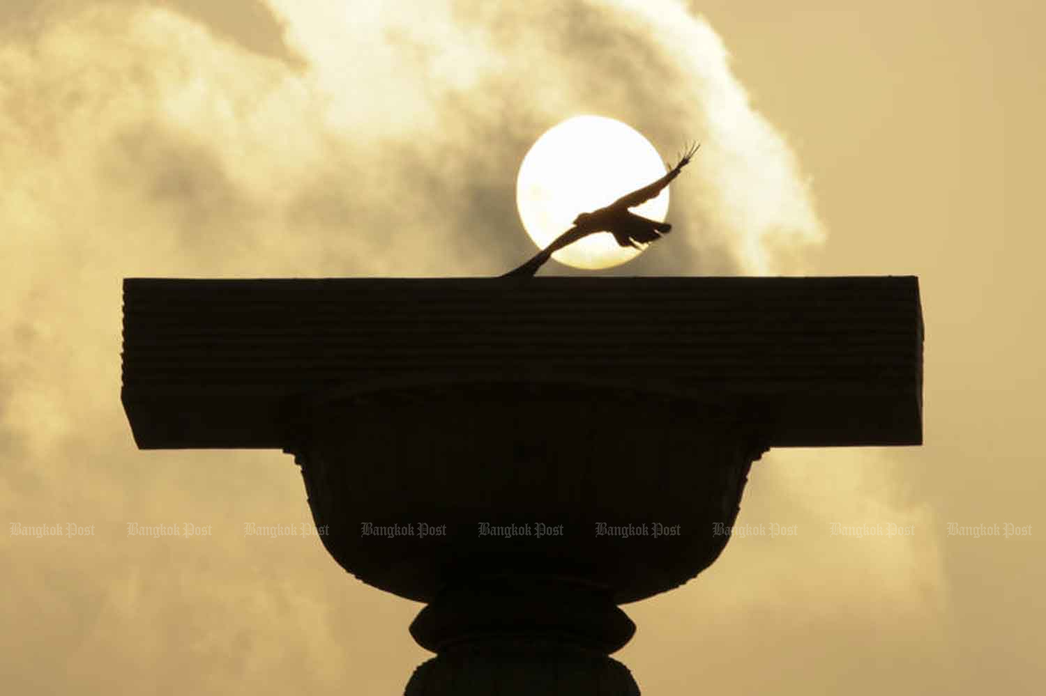 A crow flies over the Democracy Monument at dawn in 2016 as the then draft constitution was released. (File photo)