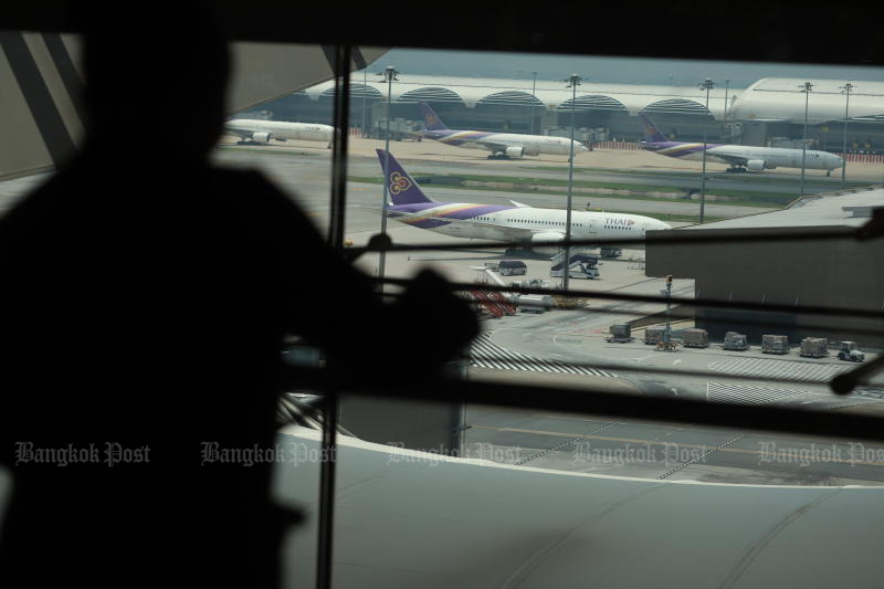 A passenger watches a Thai Airways International aircraft at Suvarnabhumi airport. (Bangkok Post file photo)