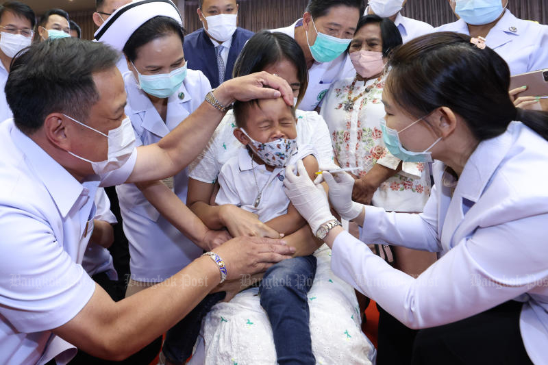 Public Health Minister Anutin Charnvirakul and medical staff try to console a boy who receives a dose of Covid-19 vaccine at Phra Nang Klao Hospital in Nonthaburi province on Oct 12, 2022. (Photo: Pornprom Satrabhaya)