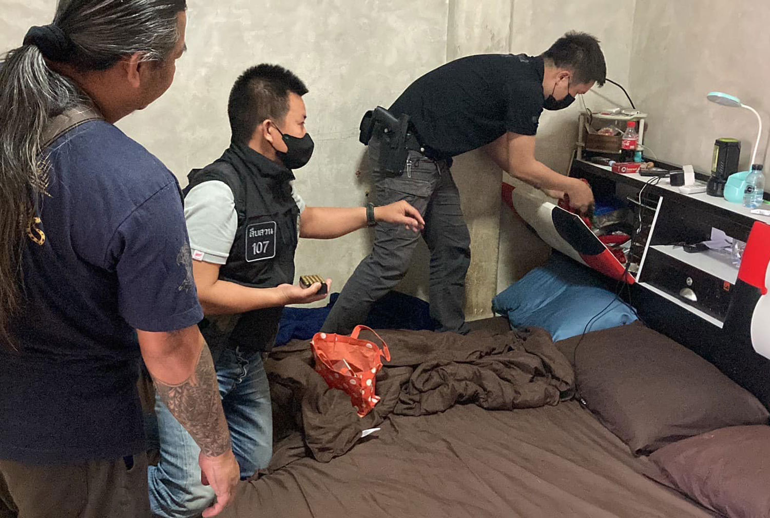 Plainclothes police search a room at one of six locations in Chiang Mai and Chiang Rai as part of an operation in which assets worth 90 million baht were seized from authorities said was a major northern drug network. (Photo: Office of the Narcotics Control Board)