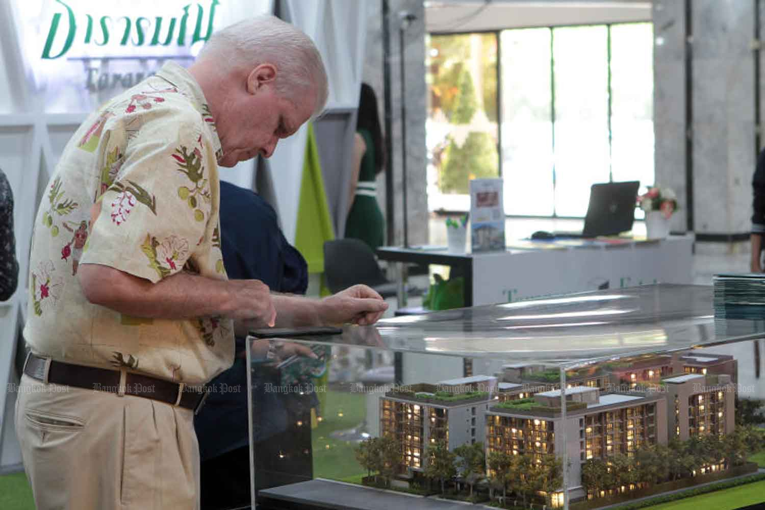 A man looks at a sales-promotion model of a low-rise condominium development at a housing fair in Bangkok. (File photo)