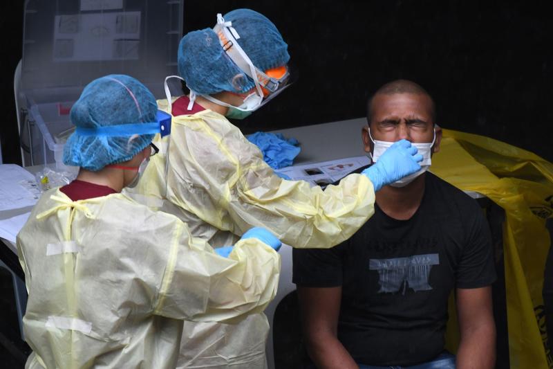 In this file photo taken on April 27, 2020, a healthcare worker dressed in personal protective equipment collects a nasal swab sample from a migrant worker for testing for the coronavirus at a foreign workers' dormitory in Singapore. (Photo: AFP)