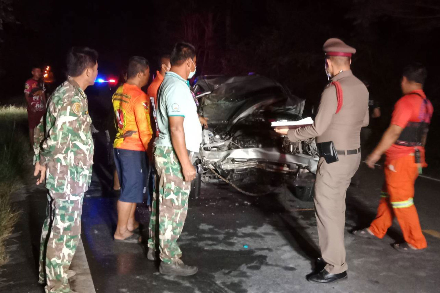 A police officer, wildlife sanctuary rangers and rescue workers inspect the pickup truck that hit a wild elephant crossing the road in Muang district, Kanchanaburi, on Friday night. (Photo: Piyarat Chongcharoen)