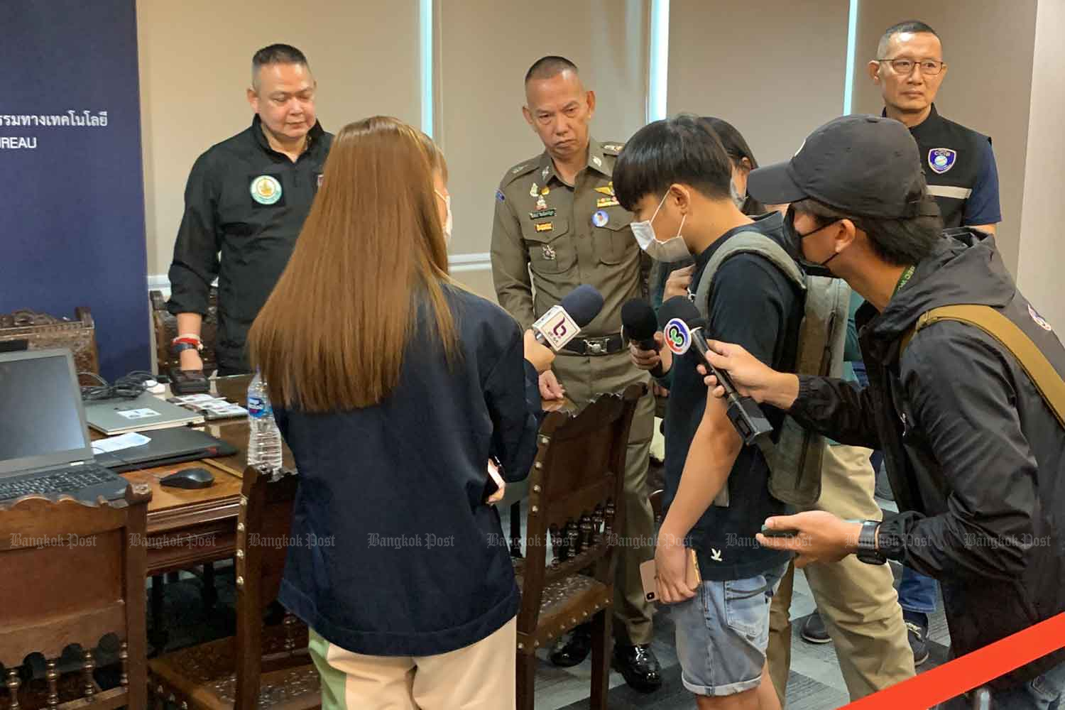 Reporters try to pose questions to the man who was arrested for alleged upskirting, at the Cyber Crime Investigation Bureau in Nonthaburi province on Tuesday. (Photo supplied)