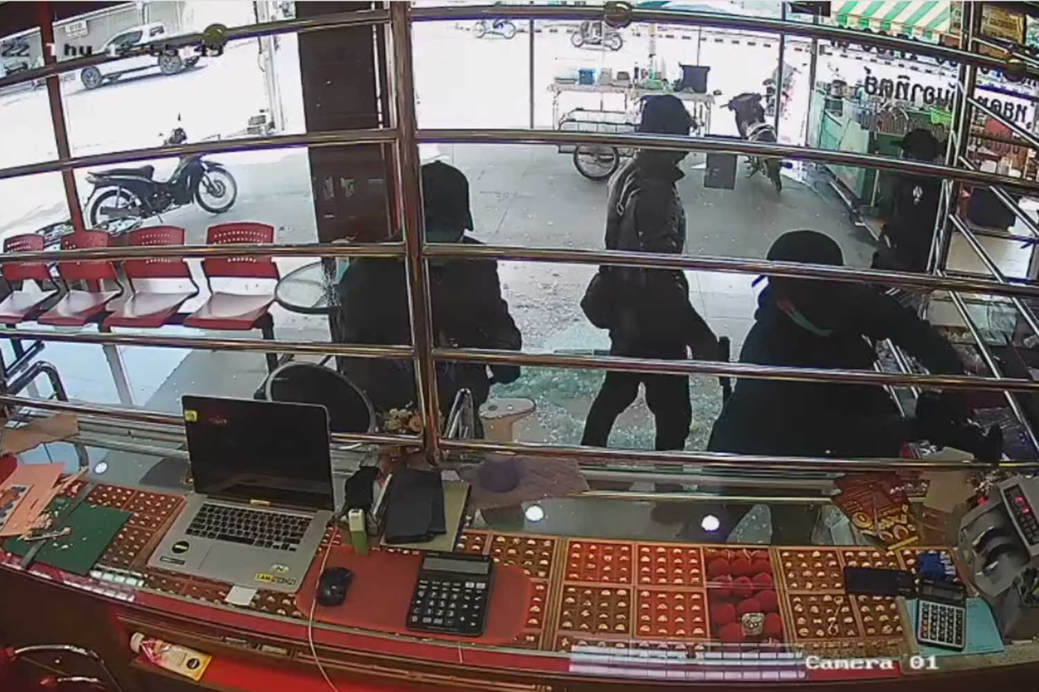 Two thieves are seen using tools to cut the steel bars at a gold shop in Muang district of Tak on Thursday afternoon, but they fled after the owner fired shots and wounded one of their accomplices. (Capture from a video posted by Ek Kiattisak Mae Sot Facebook page)